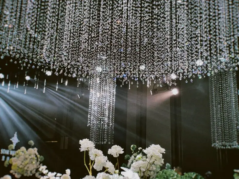 A chandelier dressed with flowers above the ceremony