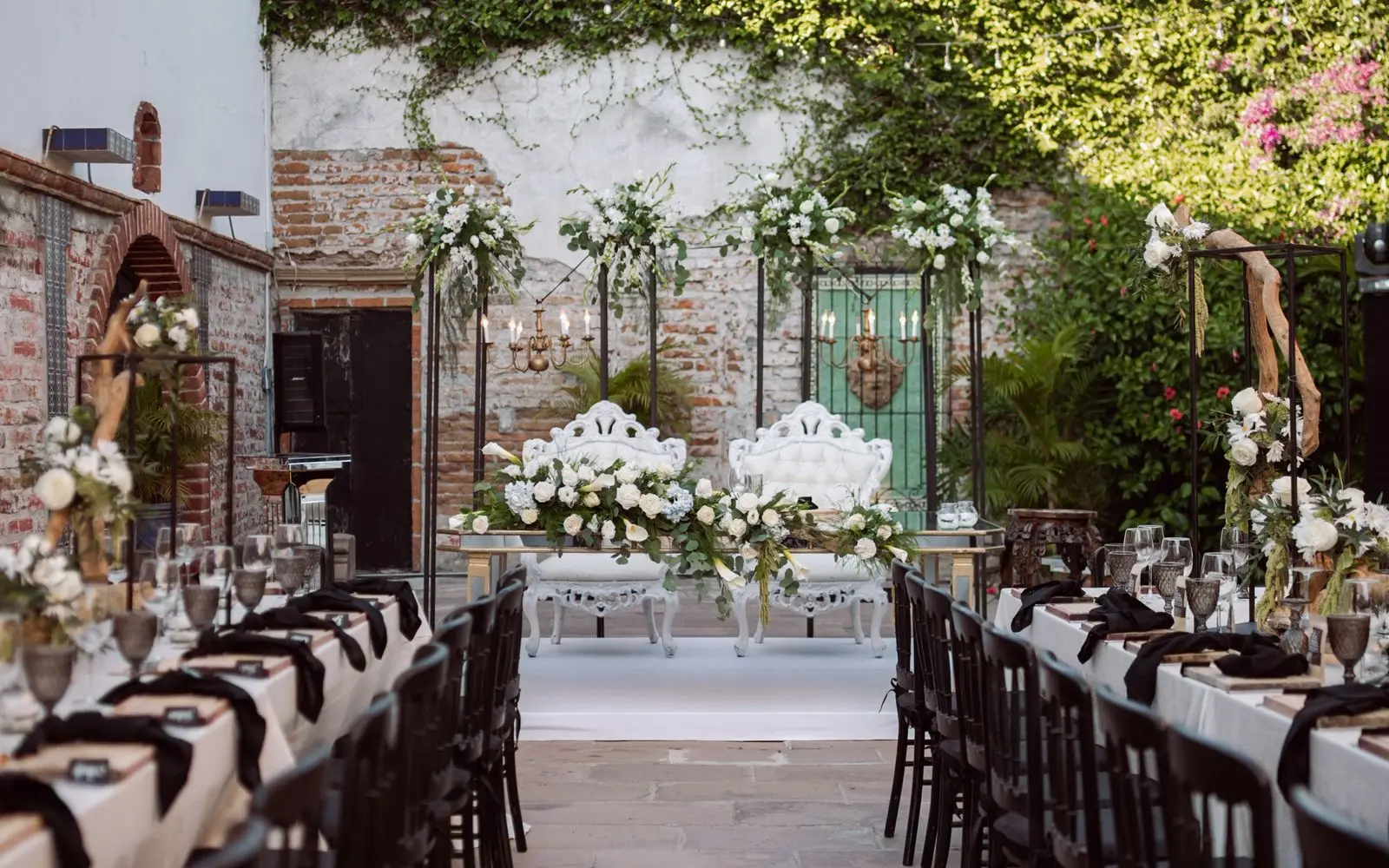 An elegant garden courtyard set for a wedding reception with long tables and florals
